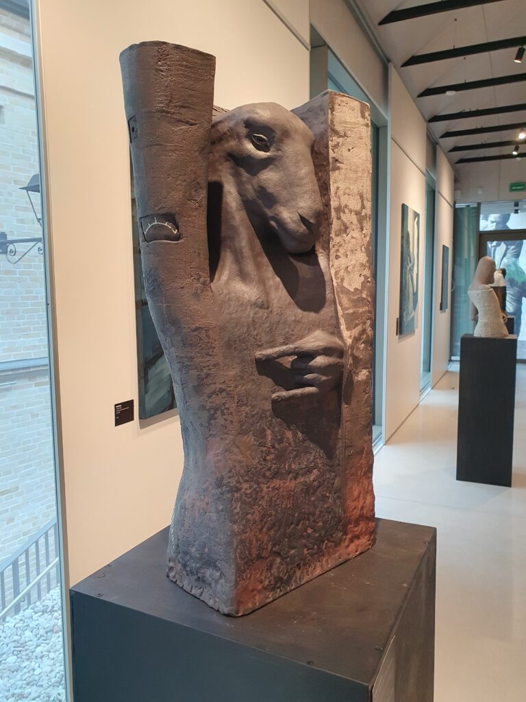 A stoneware sculpture of a musical deity in the appearance of a sheep