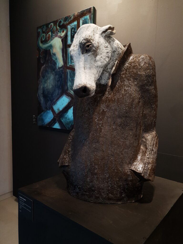 A stoneware sculpture of a mythical creature, a painting in the background